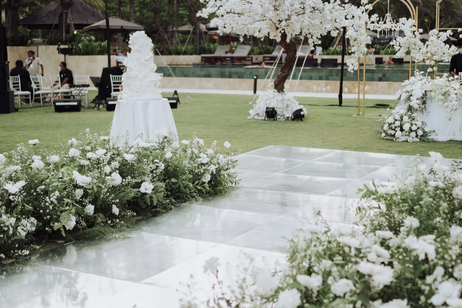 Cake table beside the mirror dance floor, white florals and blossom trees around it