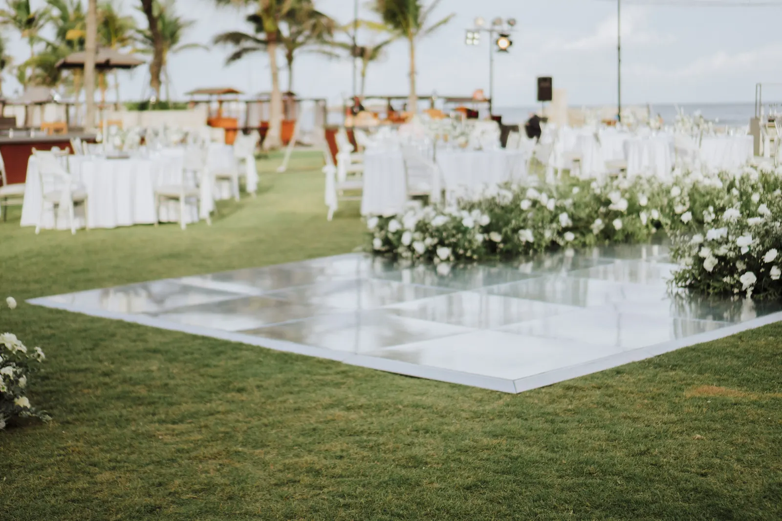 Reception tables set around the mirror dance floor, ocean beyond