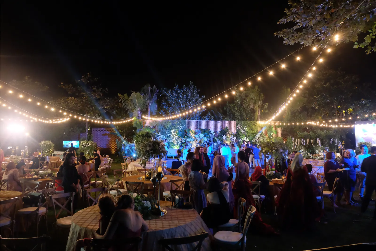 The reception at dusk under festoon lighting, guests at the tables