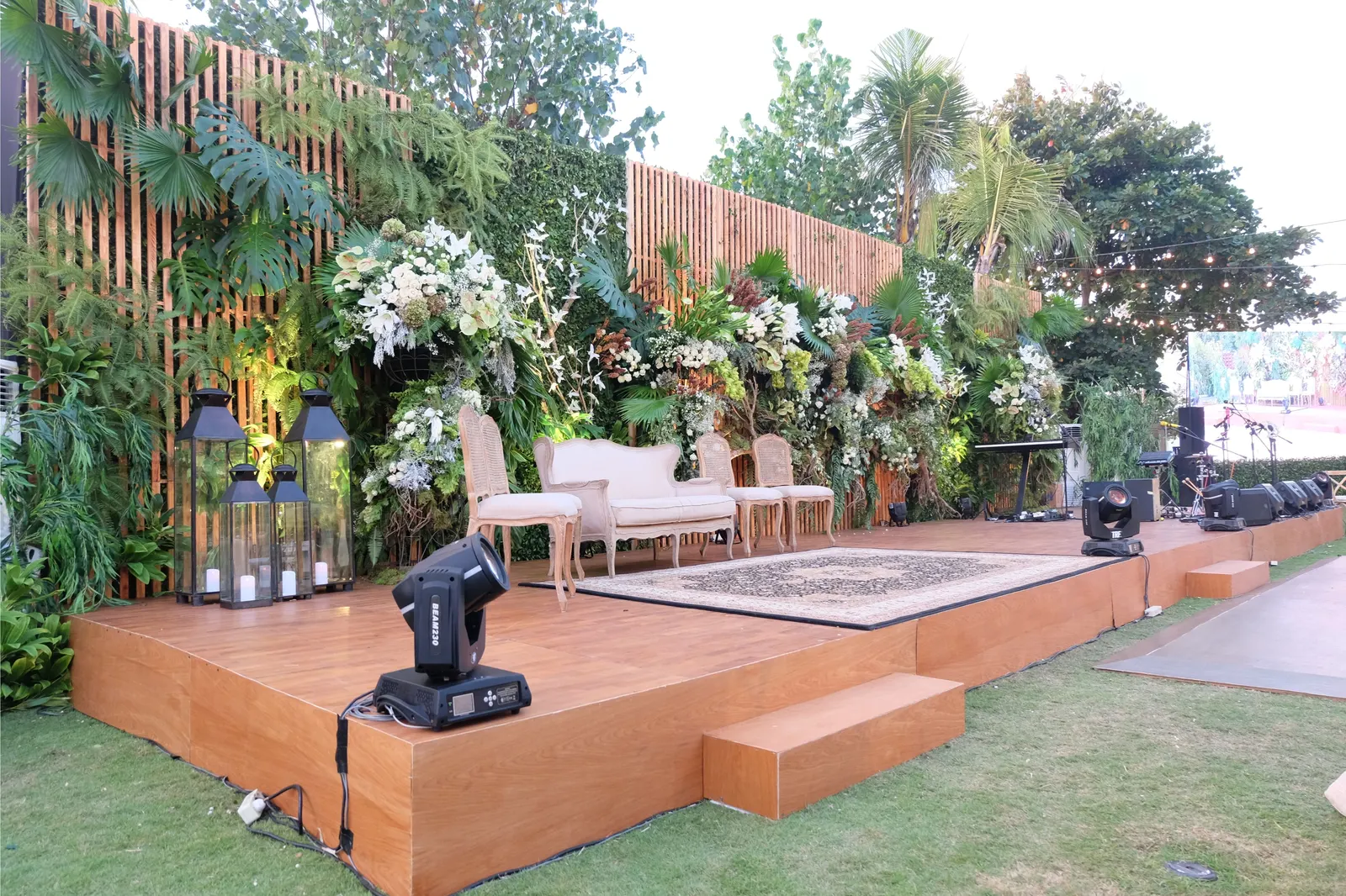 Raised timber stage dressed with florals and greenery behind the band's equipment