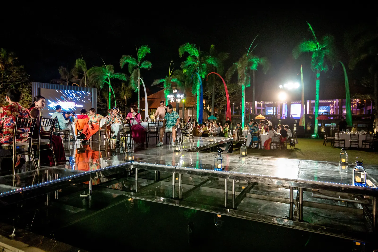Acrylic floating stage over the pool at night with guests on and around it